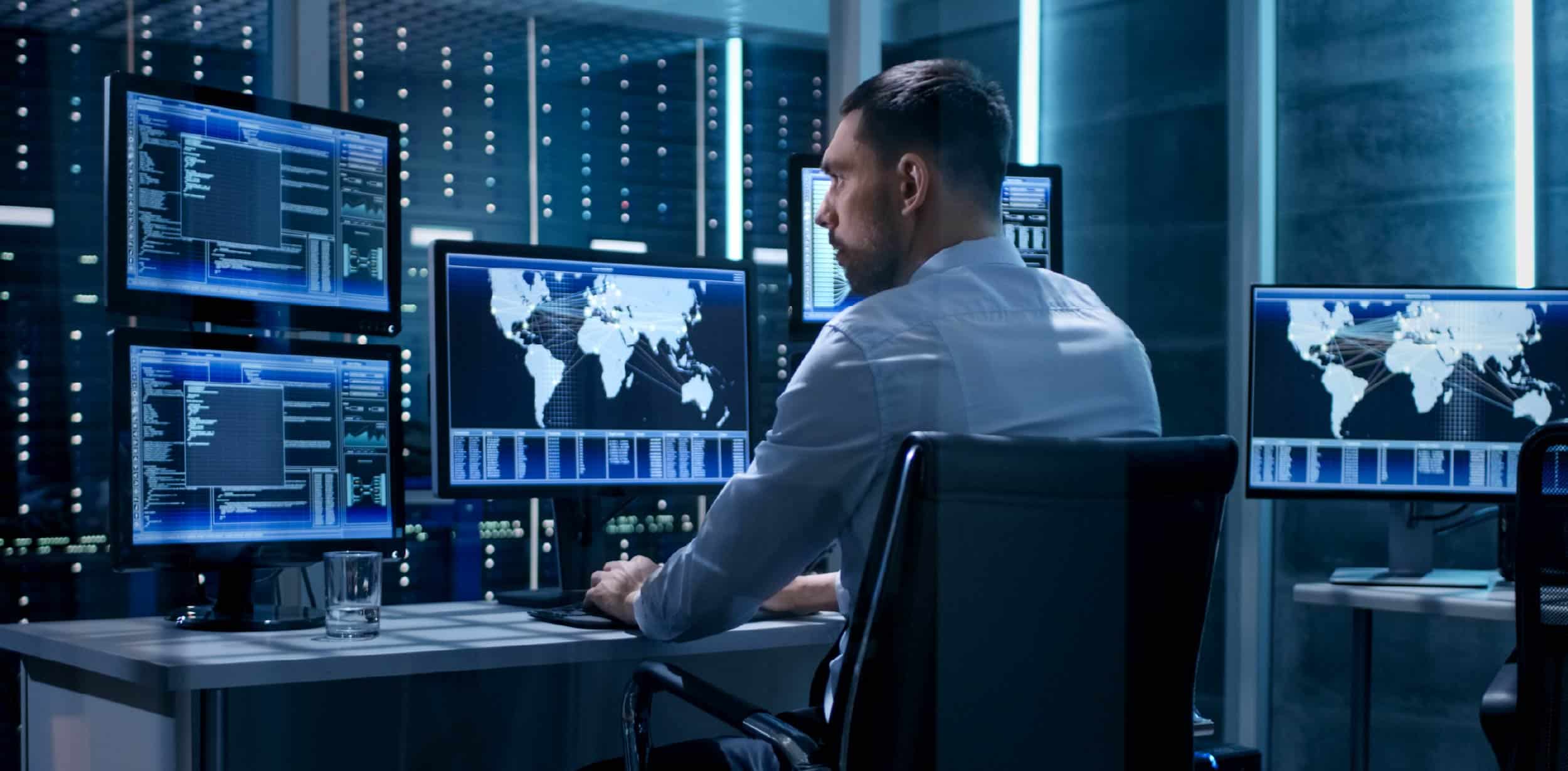 Cybersecurity analyst monitoring global threat maps and data dashboards inside a modern security operations center