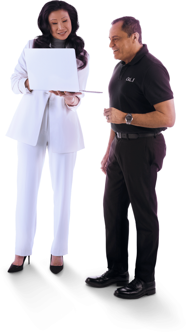 Two GLI colleagues wearing black and white business casual stand together smiling while reviewing a laptop.